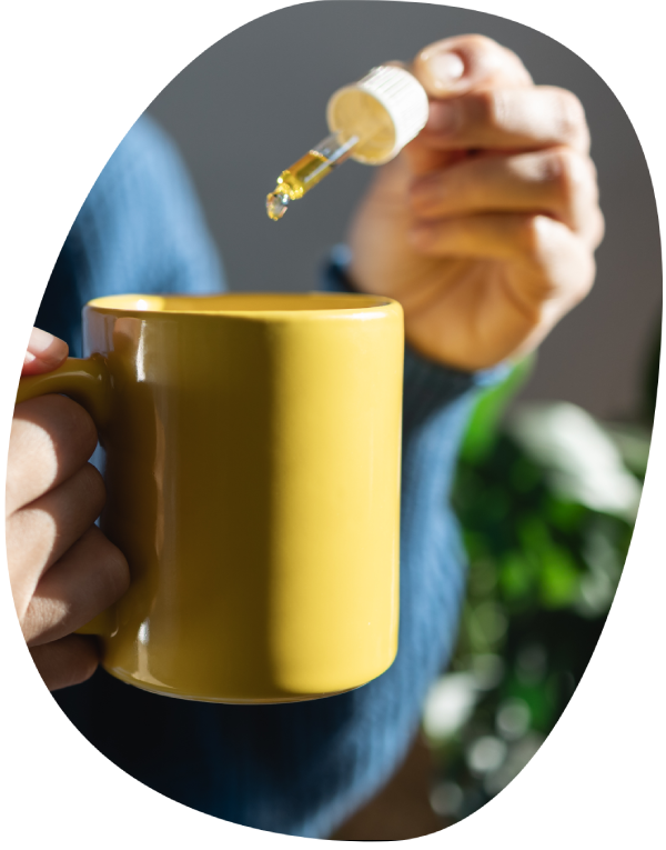 Adding mushroom tincture from a dropper into a bright mug